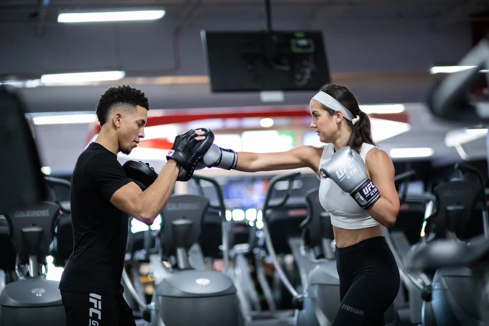 Coach UFC GYM tenant les pattes d'ours pour une adhérente