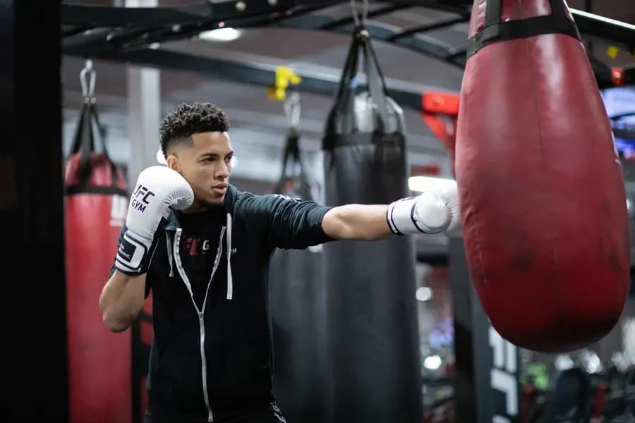 Pratiquant frappant un sac de boxe dans une salle UFC GYM