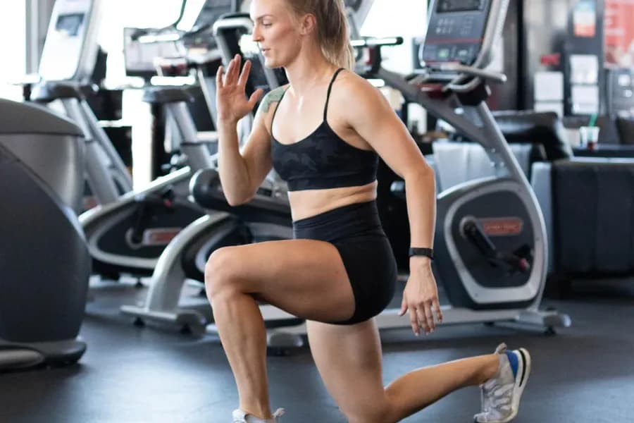 Adhérente en fente avant dans l'espace cardio d'un club UFC GYM